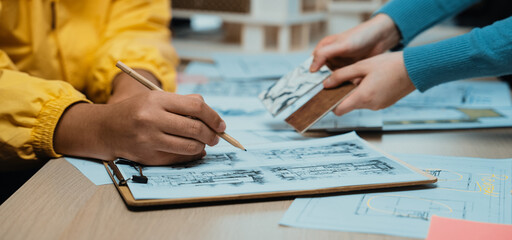 Two designers engage in a collaborative design process at a creative workspace, featuring sketches, materials, and tools that foster innovation and teamwork. SACTR