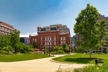 Public pedestrian space with modern buildings and lush greenery in capital city