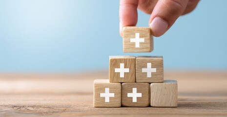 Wooden blocks with plus signs being stacked,  a hand places another block on top
