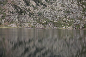 Serene mountain lake reflecting rocky cliffs and evergreen trees, offering a calm and tranquil outdoor escape for relaxation and nature lovers