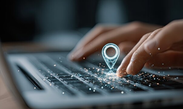 Close-up of hands typing on a laptop keyboard with a translucent location pin graphic appearing over the keys - Powered by Adobe