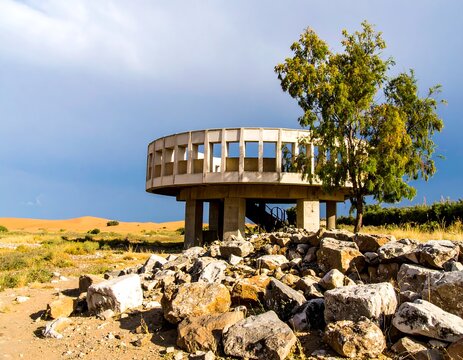 Circular concrete structure on a rocky landscape under a partly cloudy sky - Powered by Adobe