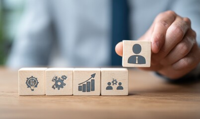 A hand places a wooden block with a person icon on top of other blocks, each with different business icons, suggesting career growth