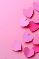 Pink paper hearts in various shades cascade against a matching pink background, creating a sweet and romantic vibe.