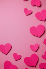 Festive pink background with paper hearts scattered around the surface, perfect for Valentine's Day or celebratory events.
