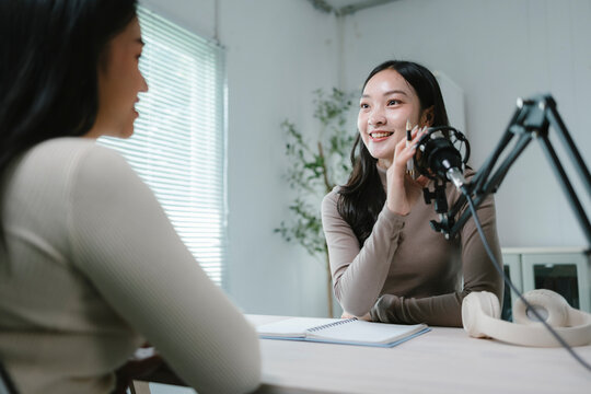 Two young women recording a podcast in a modern studio