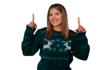 Young woman wearing festive christmas sweater pointing up, offering information, smiling on transparent background