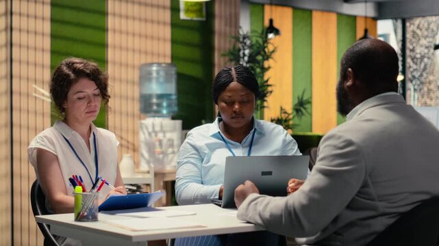 Diverse recruiters evaluating an applicant CV resume during interview session focused on selecting candidates with relevant qualifications and strong career ambition. Head hunting. Camera B.