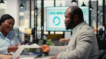 Recruiting team and an applicant engaging in CV evaluation in a business office, discussion about career experience and aspirations for growth. Interview process for professional workforce. Camera B.