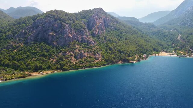 aerial perspective captures the serene beauty of Cennet Koyu, also known as Paradise Bay, in Bodrum, Turkey. Lush green hills covered in pine forests meet the crystal clear turquoise waters of the Aeg