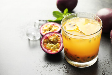 Tasty passion fruit drink with mint, ice cubes and fresh fruits on grey table, closeup. Space for text