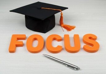Focus arranged with graduation cap and pen on a white surface