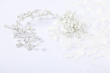 Beautiful pearl accessory and lace fabric on white background, closeup