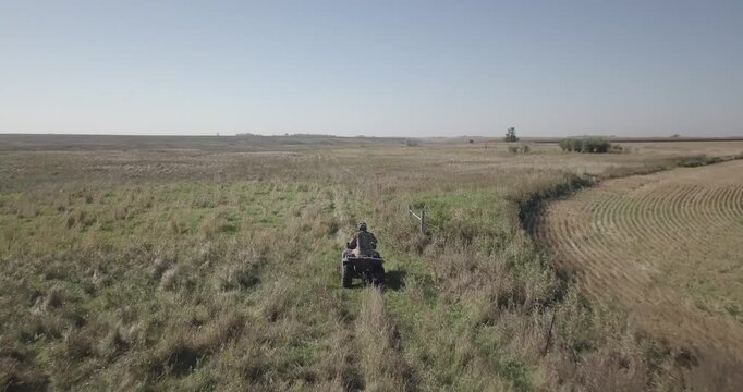 drone footage of hunter driving four wheeler ATV through prairie