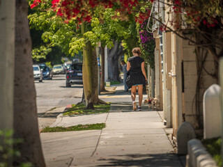 Woman walking away on a street sidewalk on a beautiful  sunny day in Los Angeles, California.