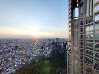Fototapeta premium 都心の高層ビルから広がる街並みを眺める夕暮れ時のパノラマ写真で右端の建物がフレームのアクセントになっています