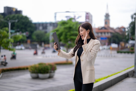 Excited businesswoman making video call on tablet in city center - Powered by Adobe