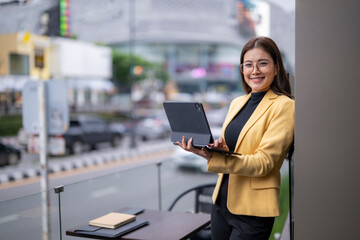Businesswoman using tablet and smiling in city cafe