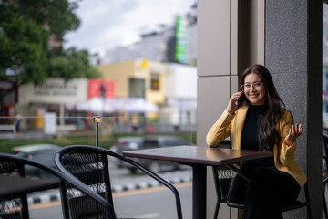 Businesswoman talking on mobile phone at outdoor cafe in urban setting