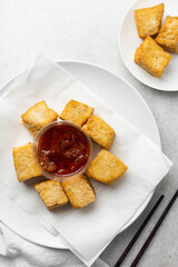 Overhead view of fried tofu with pepper sauce, top view of pan fried soya bean tofu and sauce in a white plate
