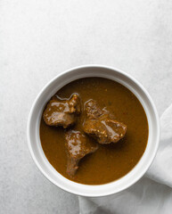 Overhead view of miyan kuka and tuwon on a white plate, top view of northern nigerian miyan kuka soup and rice swallow or tuwon shinkafa