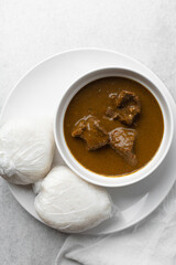 Overhead view of miyan kuka and tuwon on a white plate, top view of northern nigerian miyan kuka soup and rice swallow or tuwon shinkafa