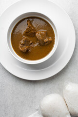 Overhead view of miyan kuka and wrapped tuwo shinkafa in a white bowl, top view of northern nigerian food and soup