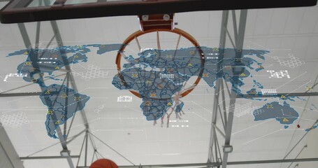 Athlete raising basketball through gym hoop, initiating digital world map overlay visualizing data - Powered by Adobe