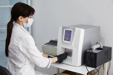 Female Research Scientist Putting Test Tube with Blood Sample into Analyzer Medical Machine. Scientist Works with Modern Medical Equipment in Laboratory
