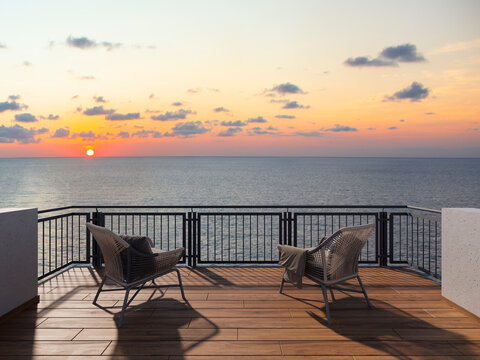 Scenic sunset view from modern balcony with two wicker chairs and cozy blanket overlooking calm sea horizon, sky with clouds, relaxing vacation mood, peaceful oceanfront terrace lifestyle. Terrace.
