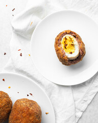 Overhead view of fried scotch eggs on white countertop, top view of cross-section of scotch eggs