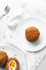 Overhead view of fried scotch eggs on white countertop, top view of cross-section of scotch eggs	