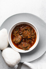 Overhead view of miyan taushe and tuwon on a white plate, top view of northern nigerian miyan taushe soup and rice swallow or tuwon shinkafa