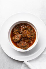 Overhead view of miyan taushe in a white bowl, top view of northern nigerian miyan taushe soup on a white countertop