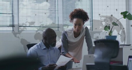 Man reading report with woman gesturing, pointing at laptop for business analysis with map overlay - Powered by Adobe