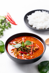 Thai red curry with pork and cooked rice with ingredients on white background