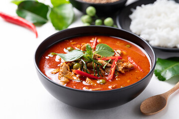Thai red curry with pork and cooked rice with ingredients on white background