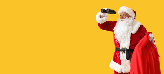 Santa Claus with Christmas bag looking through binoculars on yellow background