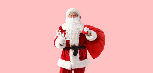 Santa Claus with Christmas bag and word XMAS on pink background