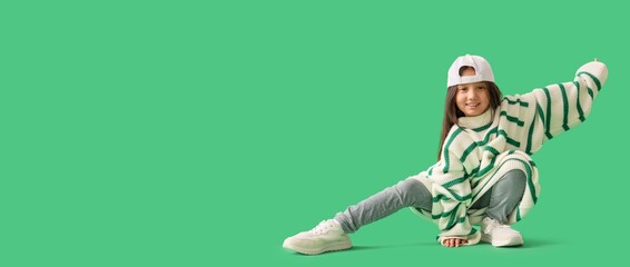 Cool little girl in oversized clothes on green background with space for text