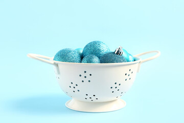 Colander with beautiful Christmas balls on color background