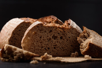 Dark rye sourdough bread sliced on black background