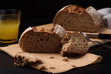 Dark rye sourdough bread sliced on black background