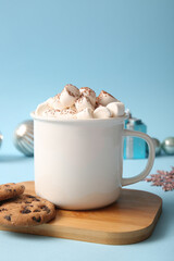 Cup of hot cocoa with marshmallows and sweet cookies on blue background