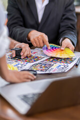 Team graphic designer checking print quality of media graphics proof print and color guides in printing industry. Selected focus