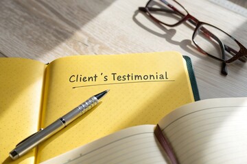 Client's testimonial written in a notebook with a pen and glasses on a wooden desk