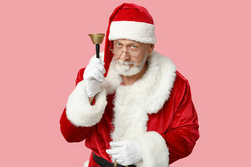 Santa Claus in glasses with Christmas bell on pink background