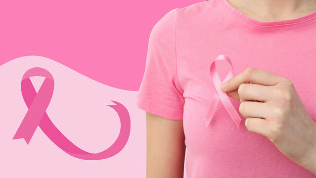 Person in pink shirt holds cancer awareness ribbon