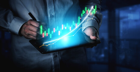 A business professional is analyzing financial graphs on a tablet, showcasing a modern office environment with blue lighting. The focus is on data analysis and market trends. Impute