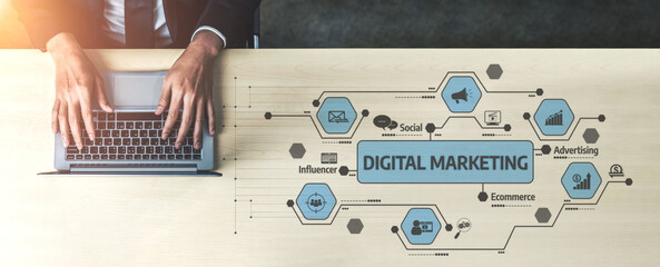 A top-down view of hands typing on a laptop with a digital marketing strategy illustrated on the...